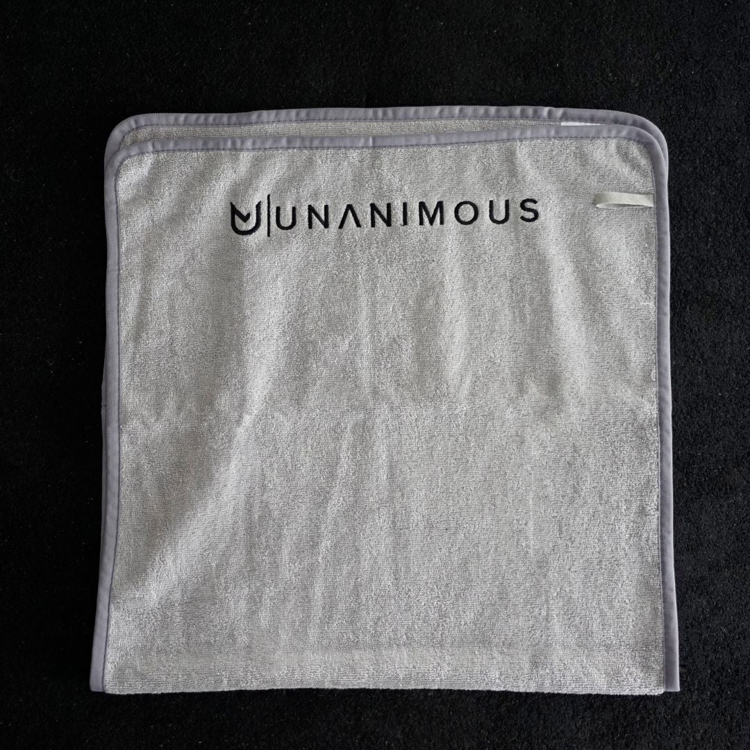 Close-up of the 25 cm sewn-on logo on the large light grey cotton workout towel.