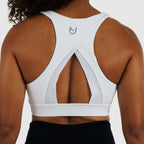 Back view of white Racerback Sports Bra on model. Highlights wide cross-strap design for maximum support and mobility