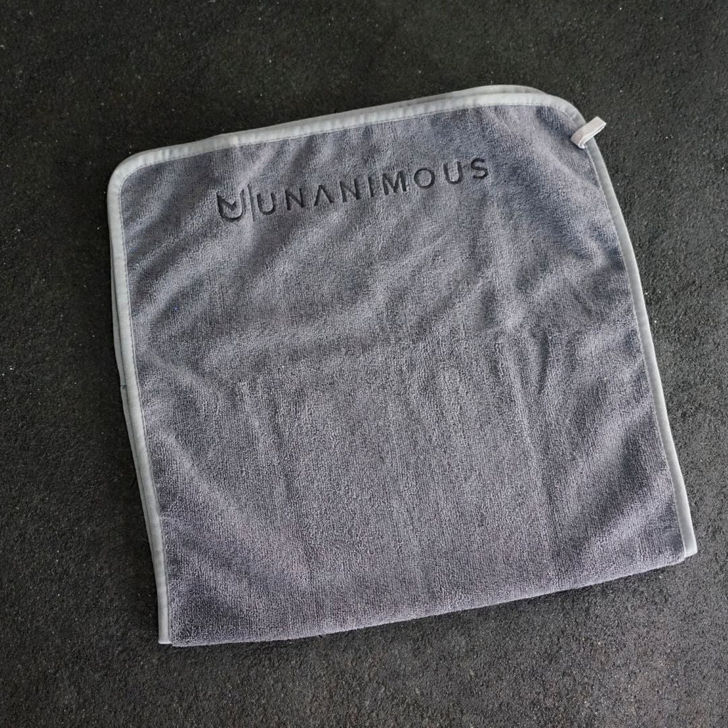 Close-up of the premium 25 cm sewn-on logo on the large dark grey workout towel.