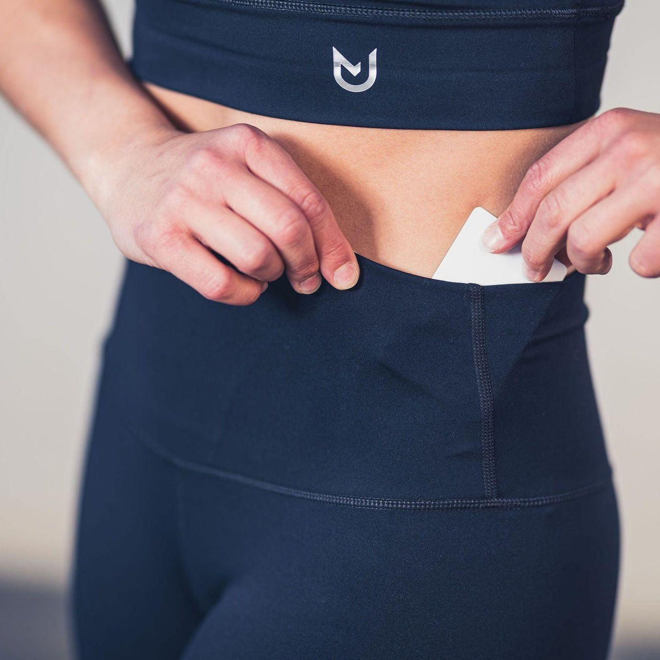 Close‑up of UNANIMOUS Sport Leggings Black fabric texture and logo detailing