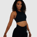 Model posing in Black High-Support Racerback Sports Bra and matching leggings. Ideal fitness outfit for training