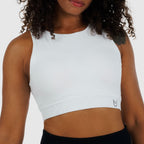Model wearing White Racerback Sports Bra. High-neckline gym top with wide underbust band for high-support training