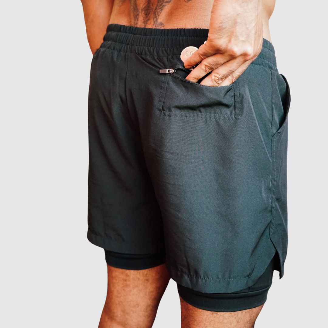 Rear view of the black 2-in-1 gym shorts, model showing the back zipper pocket.